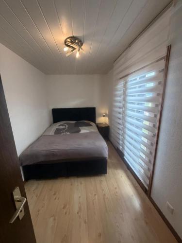 a bedroom with a bed and a window with blinds at Appolo in Vouvry