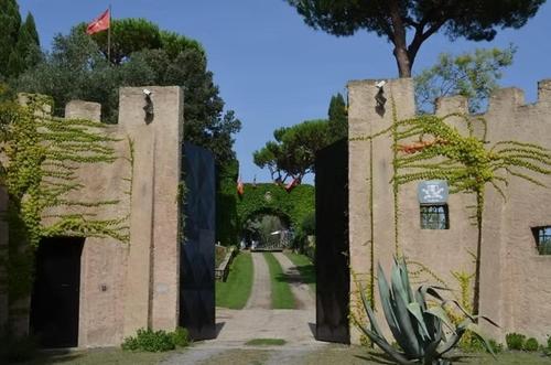 a stone building with a gate and a tree at Parco delle Nazioni - Relax Grand Resort in Castel di Decima