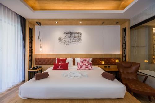 a bedroom with a large white bed and a chair at Aurico Kata Resort & Spa - SHA Extra Plus in Kata Beach
