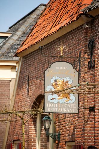a sign on the side of a brick building at Herberg de Gouden Leeuw in Bronkhorst