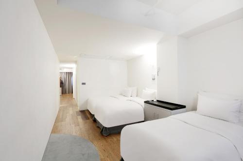two beds in a room with white walls at Hotel 498 in Incheon