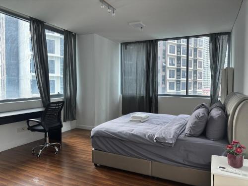 a bedroom with a bed and a chair and windows at STAR Hotel Apartment in Kuala Lumpur