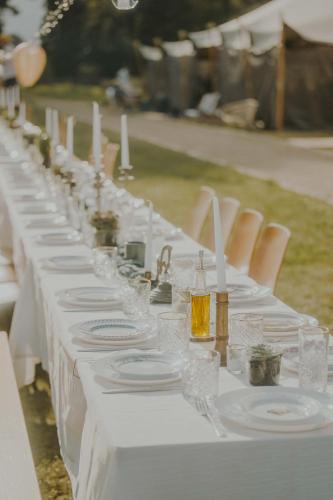a long white table with plates and wine glasses at ASTRAEA Jurt Village in Arendsee