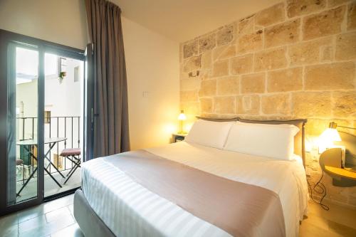a bedroom with a large bed and a stone wall at Le Contrade Di San Salvatore in Monopoli