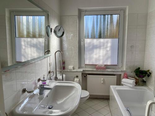 a bathroom with a sink and a toilet and two windows at Apartment am Golfplatz in Obernkirchen