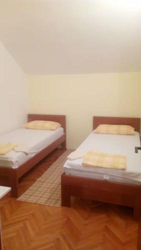 two beds in a room with wooden floors at Vacation home in Virpazar