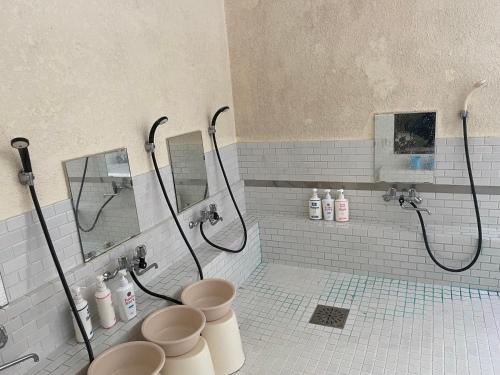 a bathroom with a shower and a toilet and mirrors at ペンション愛宕道 in Kyoto