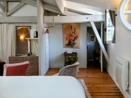 a room with a bed and a desk and a staircase at La maison botanique in Castillon-la-Bataille