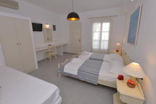 a white bedroom with a large bed and a desk at Melissa in Naousa