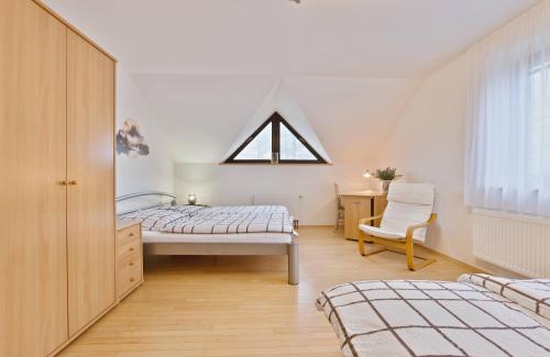 a bedroom with a bed and a window and a chair at Chalupa u golfu Kořenec in Kořenec
