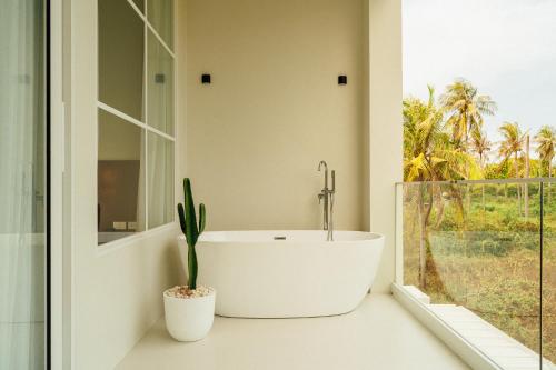 a bathroom with a tub and a plant in a window at PRAN MARE Pranburi in Ban Nong Ban Kao
