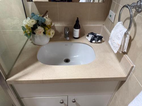 a bathroom sink with a vase of flowers and a bottle of wine at The Mosaic Tower in Manila