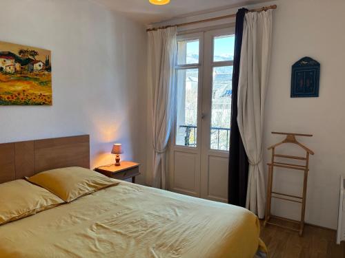 a bedroom with a bed and a large window at T2 cosy centre ville in Luchon