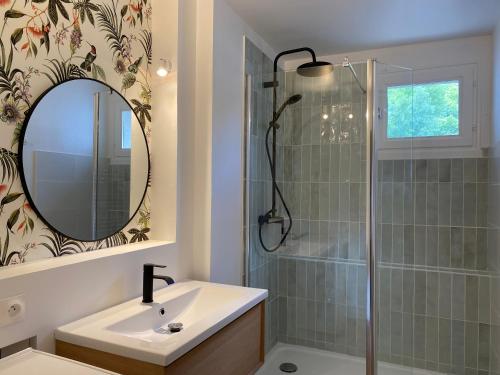 a bathroom with a sink and a shower with a mirror at T2 cosy centre ville in Luchon