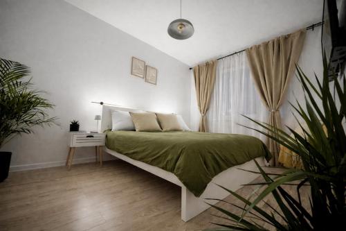 a white bedroom with a bed with a green blanket at VerdeViu Apartments 1 Prima Residence Universitatii in Oradea