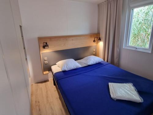 a blue bed in a room with a window at Camping de Ceyreste - Maeva in La Ciotat