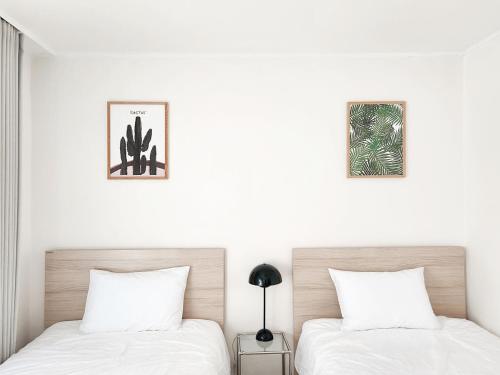 two beds in a bedroom with white walls at Kintex Central Stay 3BR 2Bath Spacious Space in Ilsan-yŏk