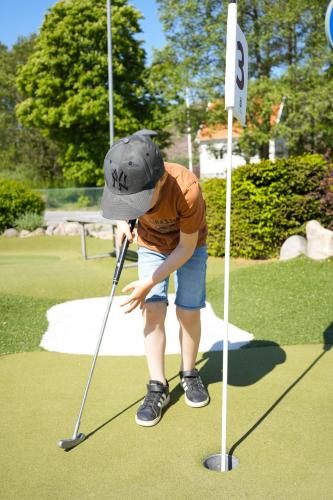 a young boy playing golf on a putting green at GrebbestadFjorden vandrarhem in Grebbestad
