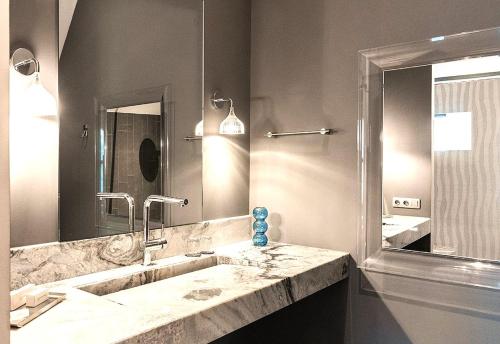 a bathroom with a sink and a large mirror at Bed & Coffee Oss Historic Weaving Mill in Oss