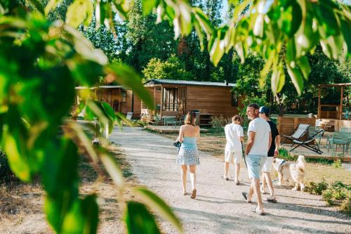 a group of people walking down a dirt road with a dog at Camping Etang de Sologne in Nouan-le-Fuzelier