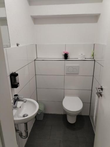 a white bathroom with a toilet and a sink at Marie Zimmer Zentral Bequem in Heilbronn