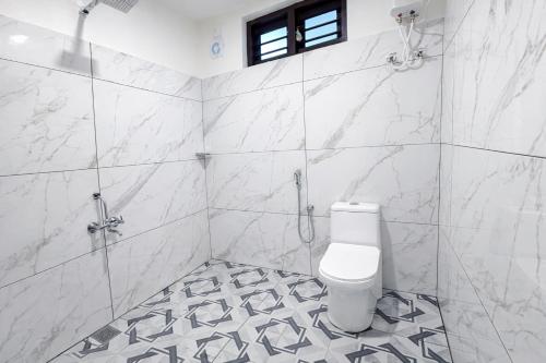 a white bathroom with a toilet and a shower at LASplore munnar in Kallar Vattiyar