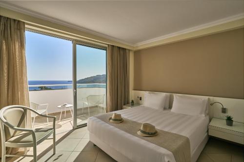 a hotel room with a bed and a large window at Lindos Village Resort & Spa - Adults Only in Lindos
