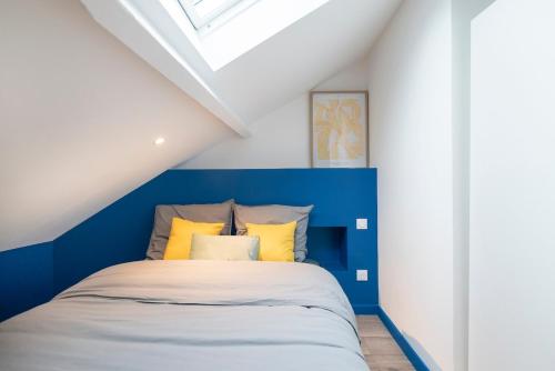 une chambre avec un lit bleu et blanc et des oreillers jaunes dans l'établissement Le Logis - 6 prs - Hyper, à Saumur