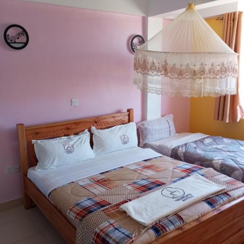 a bedroom with two beds with white walls at Tour Gate Hotel in Naro Moru