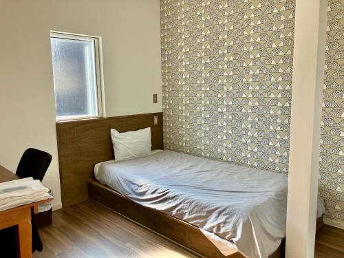ein kleines Bett in einem Zimmer mit einer Backsteinwand in der Unterkunft Lodges大黒 in Toyama