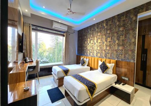 a hotel room with two beds and a desk and a window at Hotel Heritage Inn in Balasore