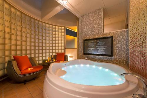 a bathroom with a tub and a chair in a room at ホテルルアン横浜 in Kikuna