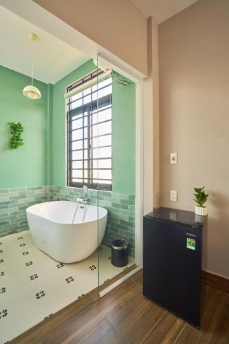 a bath tub in a bathroom with green walls at Minh Nhat Villa - 3S Villa in Cồn Giả Viên