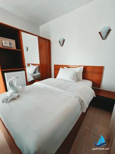 a bedroom with two white beds and a mirror at نادي البحارة الدولي - International Seamans Club in Suez