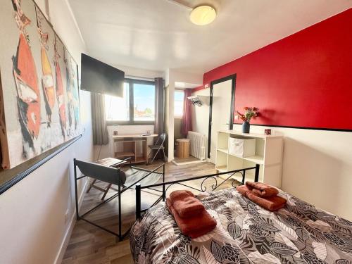 a bedroom with a red wall with a bed and a desk at Chez Mamie Cloclo in Calais