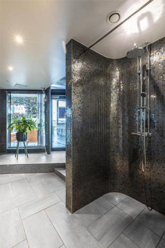 ein Bad mit einer Dusche und gefliesten Wänden in der Unterkunft Radisson Blu Riverside Hotel in Göteborg