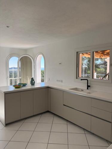 a kitchen with white cabinets and a sink and windows at Villa Casiopea in Illes Balears