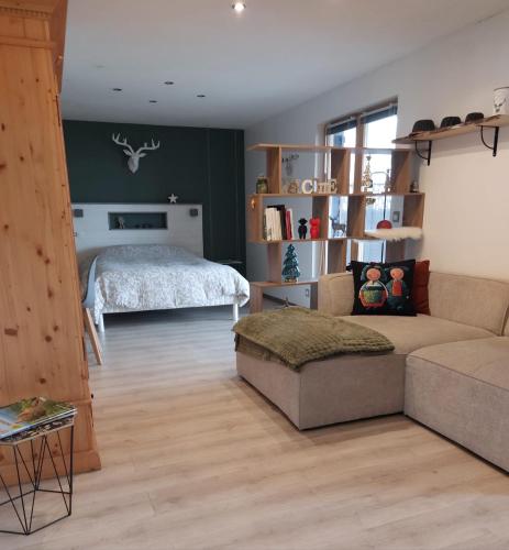 a living room with a bed and a couch at Le chalet de cathy in Soultzeren
