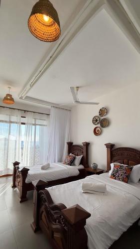 a bedroom with two beds and a chandelier at Sultan Palace Beach Resort - AMANI Apartment CB2-202 in Kikambala