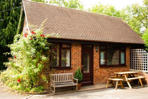 a small brick house with a bench and a picnic table at Tovey Lodge in Hassocks