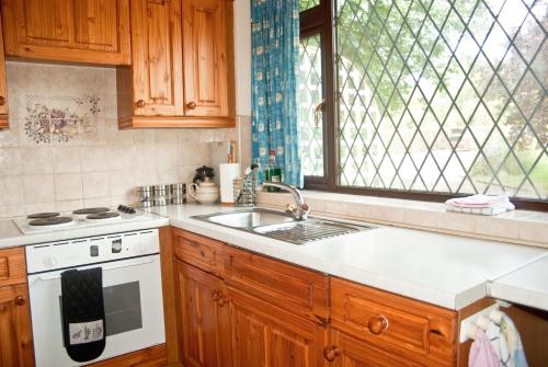 a kitchen with a sink and a stove and a window at Tovey Lodge in Hassocks