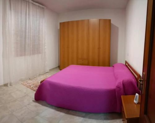 a bedroom with a purple bed and a wooden cabinet at Casa Nonno Maiti in Scardovari