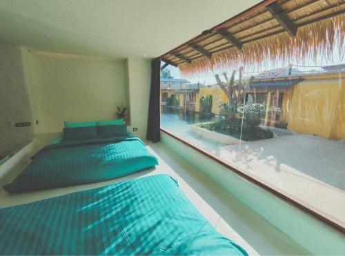 a bedroom with a bed and a large window at Sibsansmuth Resort in Ko Larn