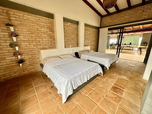 two beds in a room with a brick wall at Casa Boutique Calima in Restrepo