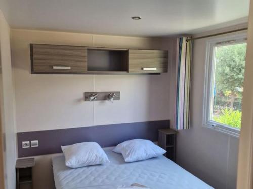 a bedroom with a bed with two pillows and a window at Camping La Provençale - Maeva in Mandelieu-La Napoule