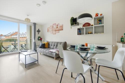 a living room with a table and a couch at Steps from Train Station - Modern 2-Bedroom with Balcony & Cambridge Amenities, Family Friendly in Cambridge