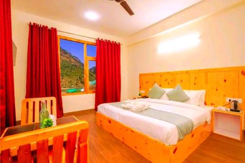 a bedroom with a large bed with red curtains at Pinnacle view in Manāli