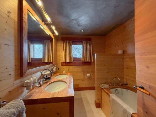 a bathroom with two sinks and a bath tub and a tubermott at Chalet Sainfoin in Verbier