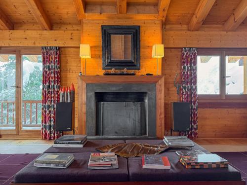 a living room with a fireplace and a table with books at Chalet Sainfoin in Verbier