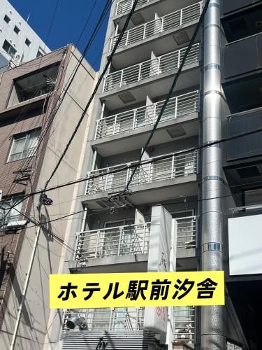 a sign on a pole in front of a building at ホテル駅前汐舎 in Nagasaki